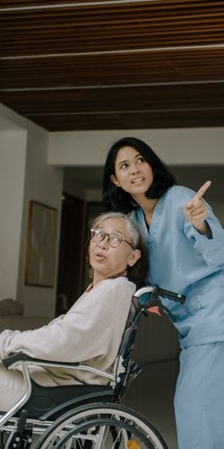 a senior woman as in a wheelchair with a caregiver. 7 End-of-Life Considerations for Seniors