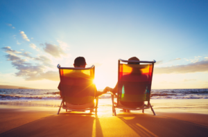 Retired couple finding the time to relax in the sun on the beech during retirement.