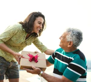 A senior parent and daughter exchanging a gift.